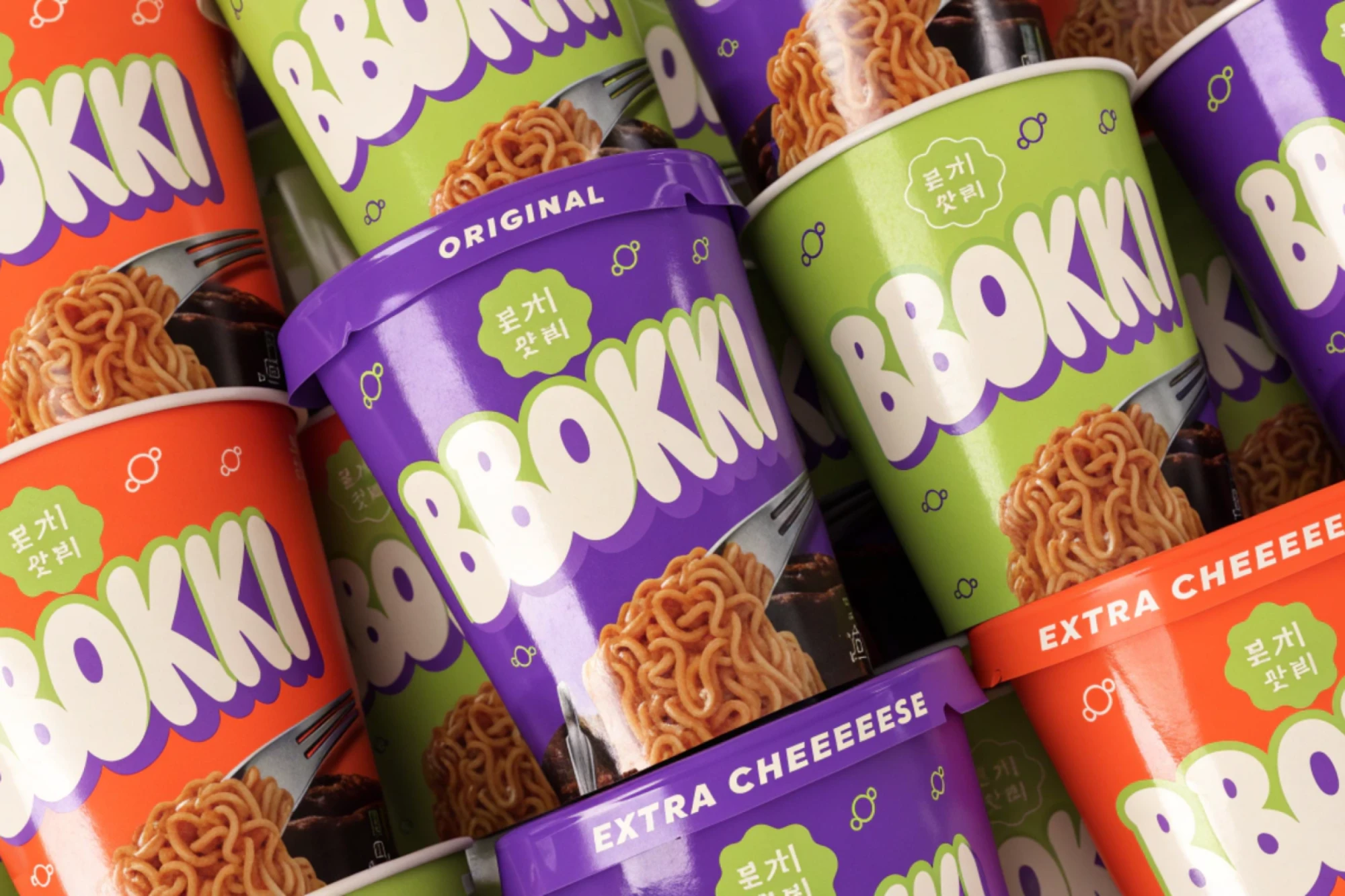 BBOKKI, a pile of orange, green and purple tteokbokki cups