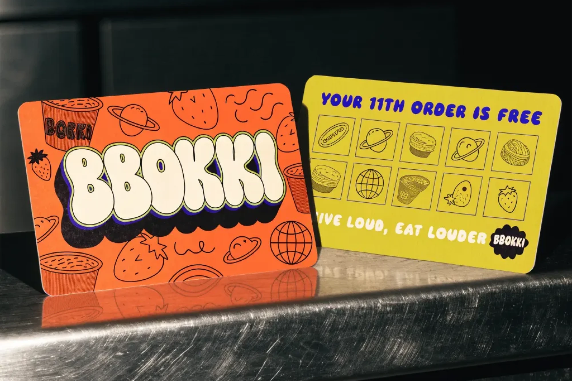 BBOKKI, orange and yellow loyalty cards on a steel counter